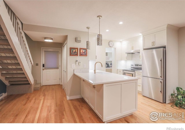 kitchen featuring white cabinetry, kitchen peninsula, stainless steel appliances, light hardwood / wood-style flooring, and decorative light fixtures