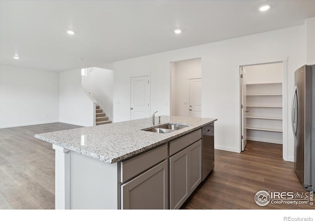 kitchen with dark hardwood / wood-style flooring, stainless steel appliances, a center island with sink, and sink