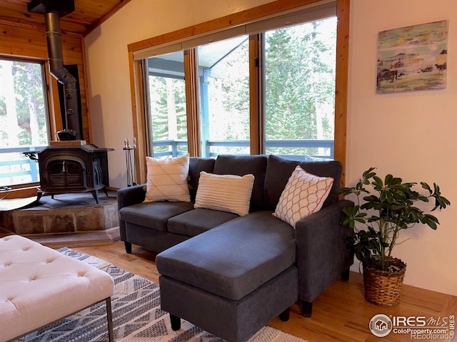 living room with a wood stove, lofted ceiling, and light wood-type flooring