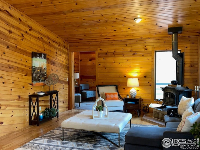 living room featuring wooden walls, hardwood / wood-style floors, a wood stove, and wooden ceiling