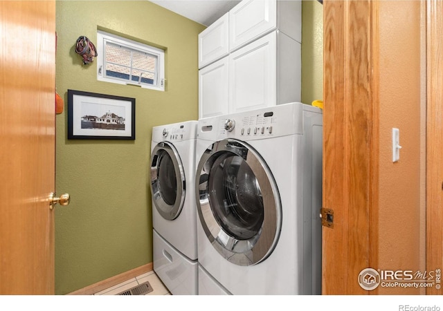 laundry room featuring cabinets, tile patterned flooring, and washing machine and dryer