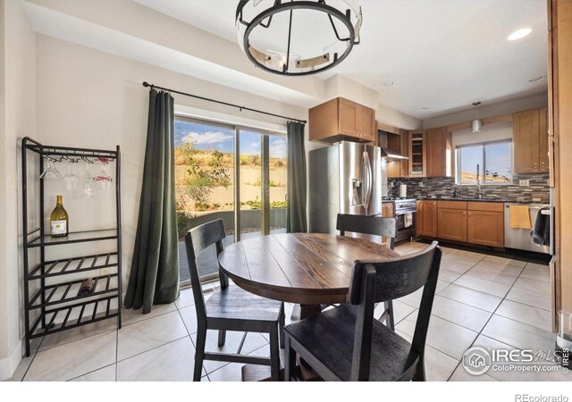 tiled dining room featuring plenty of natural light, an inviting chandelier, and sink