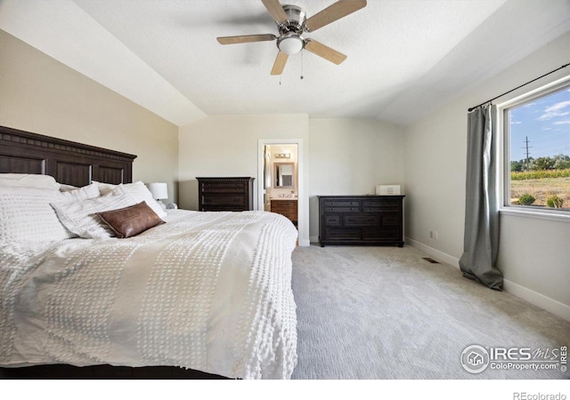 bedroom with ceiling fan, ensuite bathroom, light carpet, and vaulted ceiling