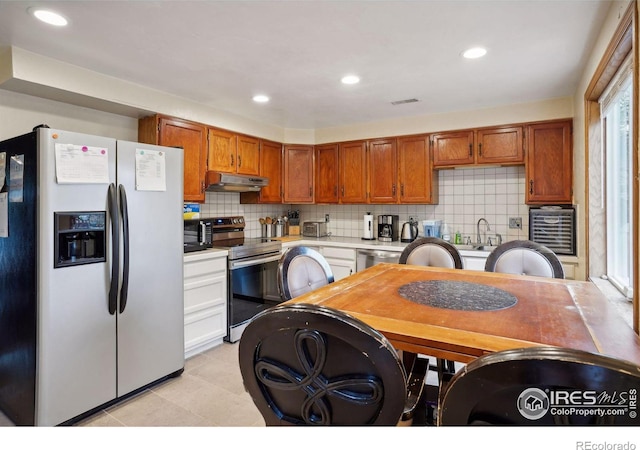 kitchen with sink, stainless steel appliances, light tile patterned flooring, and decorative backsplash