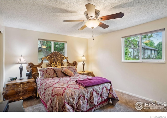 carpeted bedroom featuring a textured ceiling, ceiling fan, and multiple windows