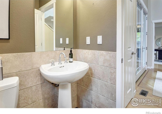 bathroom with toilet and tile walls