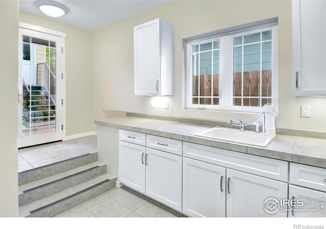 kitchen with white cabinets, sink, and light tile patterned floors