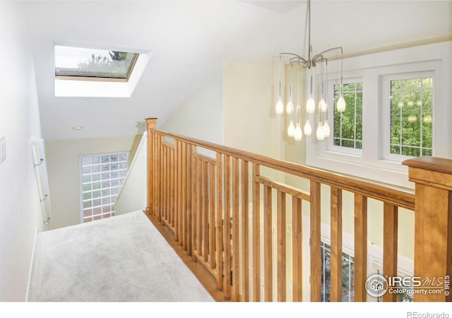 hallway featuring lofted ceiling with skylight and a chandelier