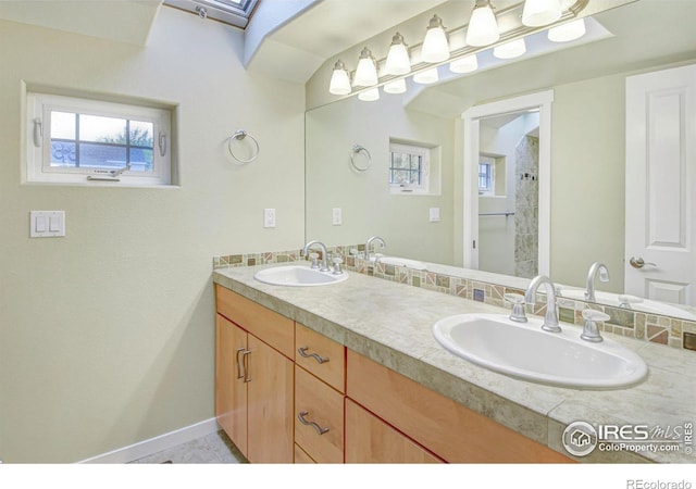 bathroom with vanity, a tile shower, and a skylight