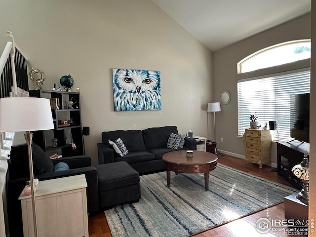 living room with baseboards, high vaulted ceiling, and wood finished floors