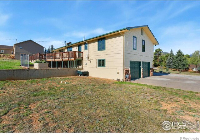 back of house featuring a yard, a garage, and a wooden deck