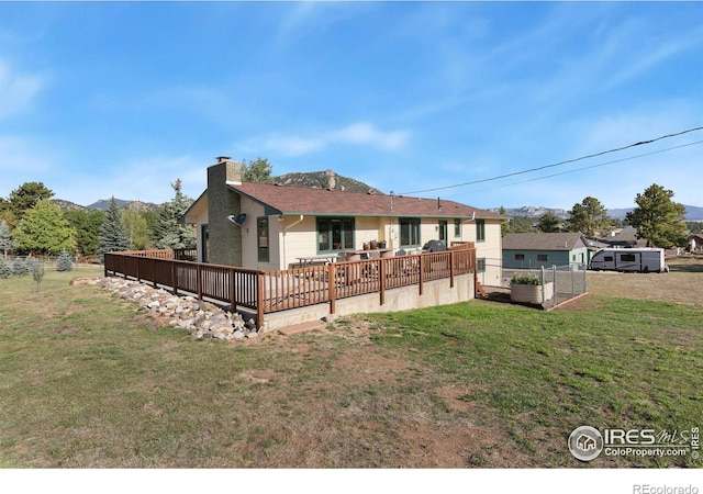 back of house featuring a deck with mountain view and a lawn