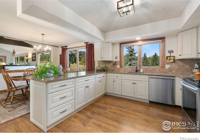 kitchen with sink, stainless steel appliances, white cabinetry, and kitchen peninsula