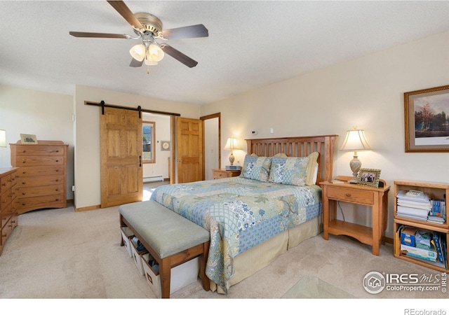 carpeted bedroom featuring ceiling fan and a barn door