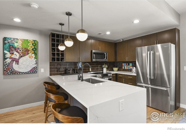 kitchen with hanging light fixtures, kitchen peninsula, dark brown cabinetry, and stainless steel appliances