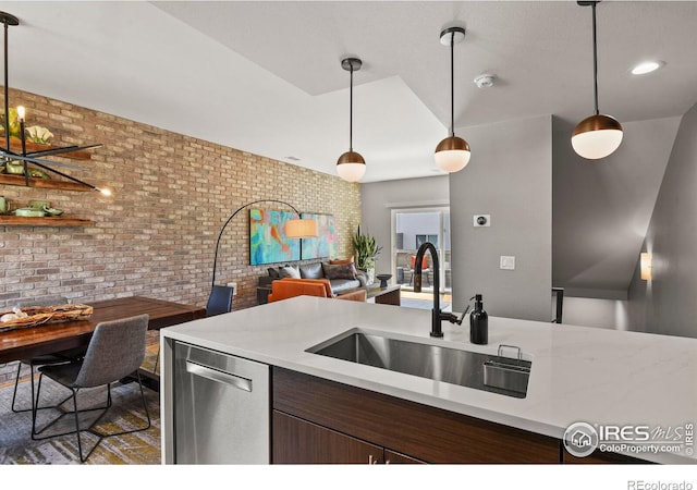 kitchen featuring dishwasher, brick wall, sink, and decorative light fixtures