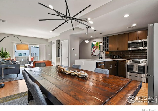 dining room featuring sink, light wood-type flooring, and a chandelier