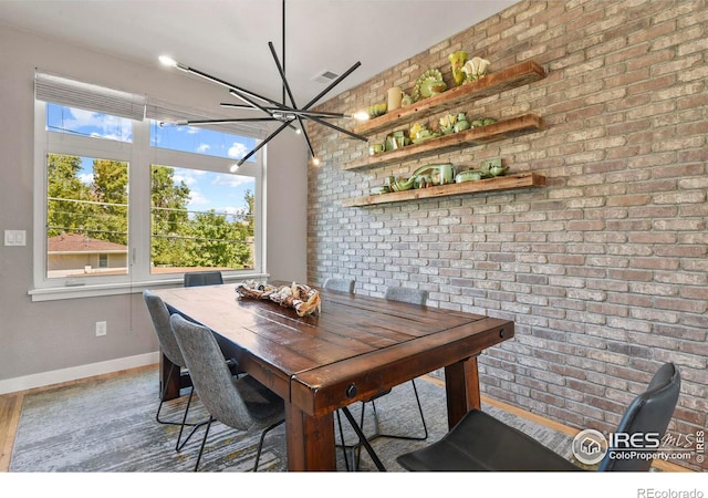 dining area featuring wood-type flooring and brick wall