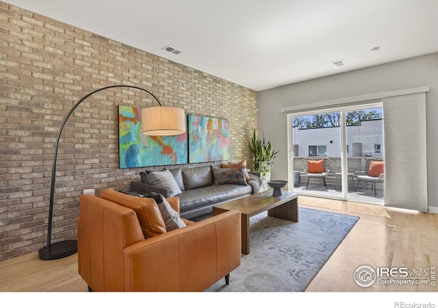 living room with light wood-type flooring and brick wall