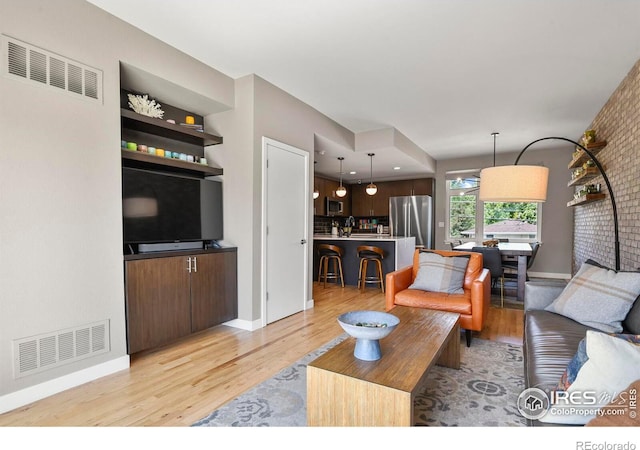 living room with brick wall and light hardwood / wood-style floors