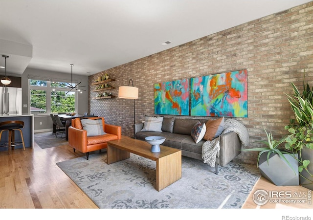 living room with brick wall and hardwood / wood-style flooring