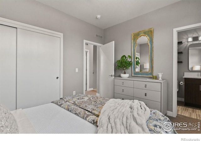 bedroom featuring hardwood / wood-style floors, ensuite bathroom, and a closet