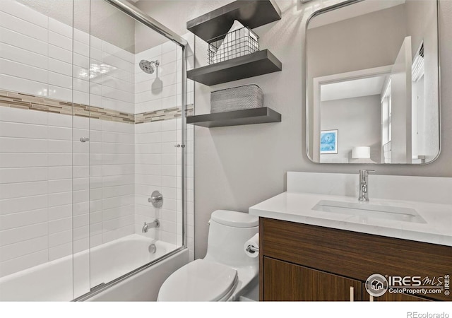 full bathroom with combined bath / shower with glass door, vanity, and toilet