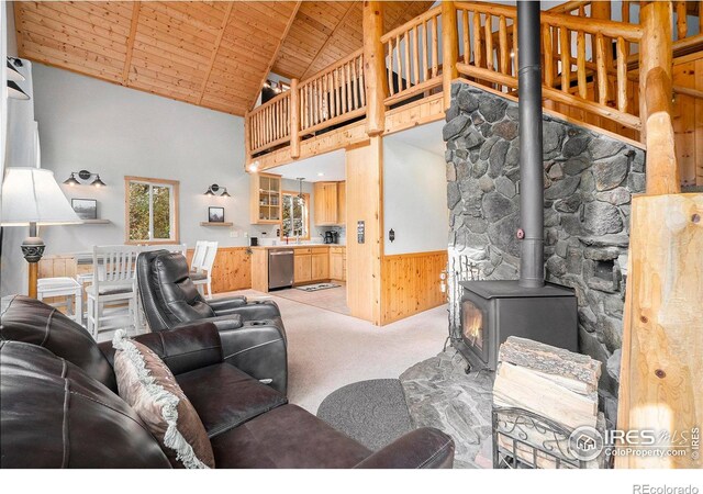 carpeted living room featuring wood ceiling, wooden walls, beam ceiling, high vaulted ceiling, and a wood stove