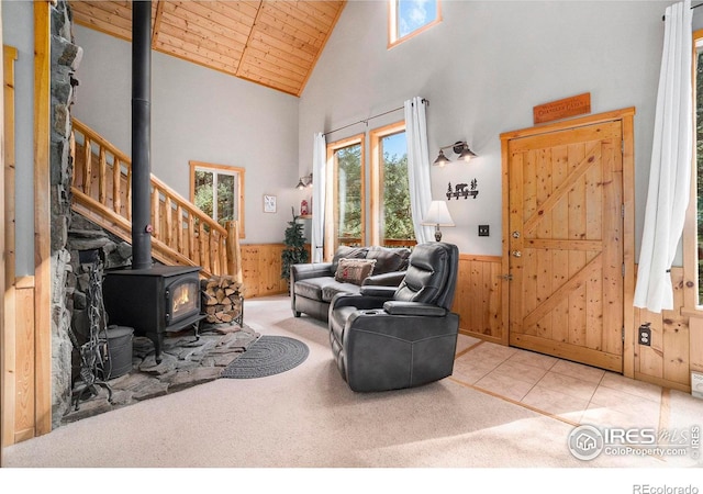 living room with wood walls, a wood stove, light carpet, high vaulted ceiling, and wooden ceiling