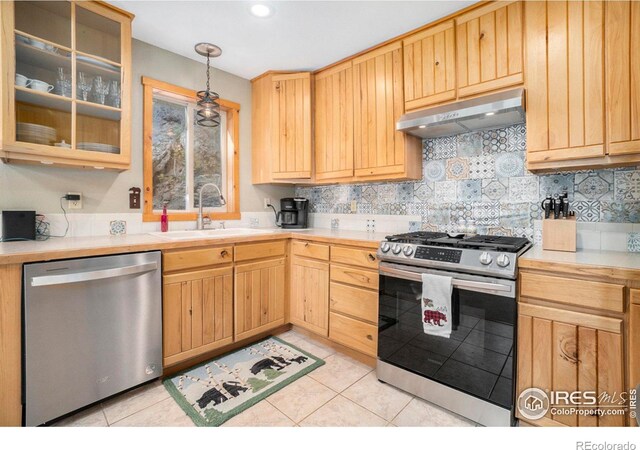 kitchen featuring sink, hanging light fixtures, backsplash, light tile patterned flooring, and appliances with stainless steel finishes