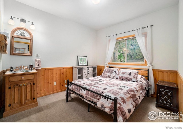 carpeted bedroom featuring wooden walls