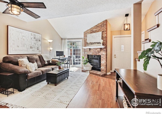 living room featuring lofted ceiling, ceiling fan, a fireplace, and wood-type flooring