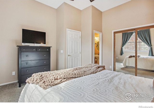 carpeted bedroom with a towering ceiling, a closet, and ensuite bath