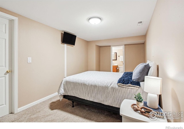 bedroom with connected bathroom and carpet floors