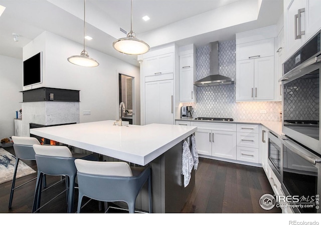 kitchen with white cabinetry, appliances with stainless steel finishes, dark hardwood / wood-style floors, decorative backsplash, and wall chimney exhaust hood