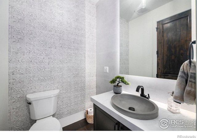 bathroom featuring vanity, toilet, and tile walls