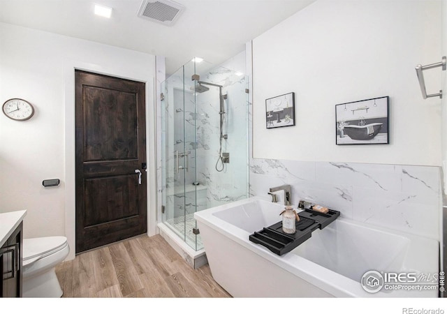 full bathroom featuring hardwood / wood-style floors, shower with separate bathtub, vanity, and toilet