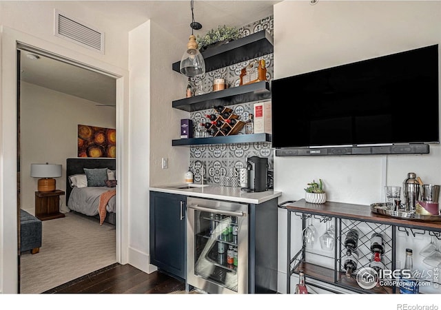 bar with wine cooler, decorative light fixtures, dark wood-type flooring, and sink