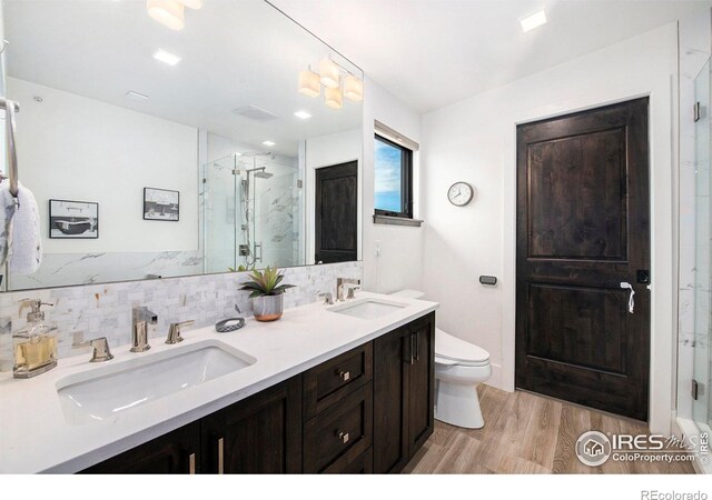 bathroom featuring walk in shower, vanity, decorative backsplash, and wood-type flooring