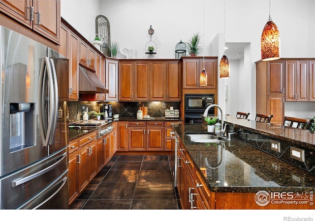 kitchen featuring a kitchen island with sink, pendant lighting, backsplash, stainless steel appliances, and sink