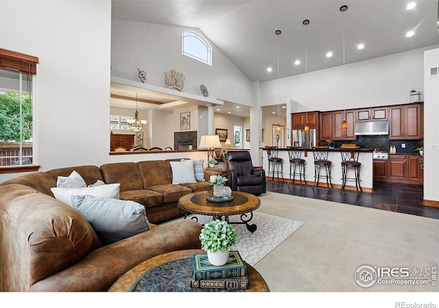 living room featuring dark wood-type flooring, high vaulted ceiling, a wealth of natural light, and a chandelier