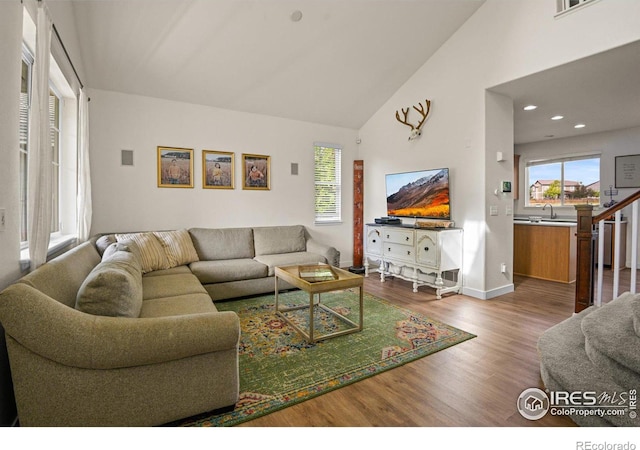 living room with high vaulted ceiling, sink, and wood-type flooring