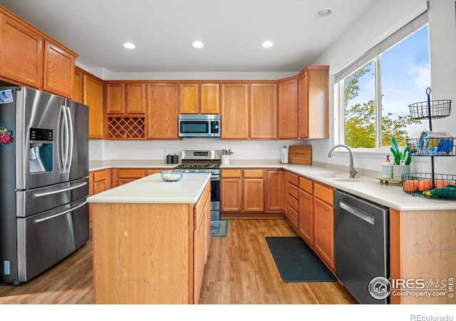 kitchen with a center island, stainless steel appliances, light hardwood / wood-style floors, and sink