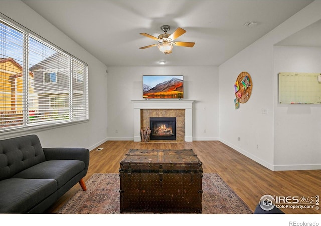 living room featuring ceiling fan, a fireplace, and light hardwood / wood-style flooring