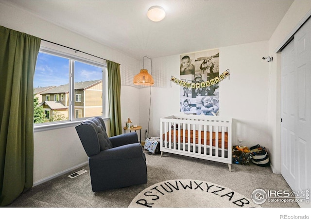 carpeted bedroom with a crib and a closet