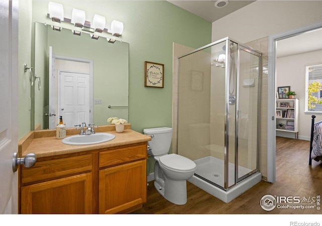 bathroom featuring a shower with shower door, toilet, vanity, and hardwood / wood-style flooring