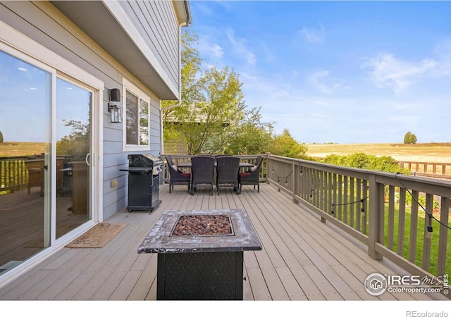 deck with area for grilling, a rural view, and an outdoor fire pit