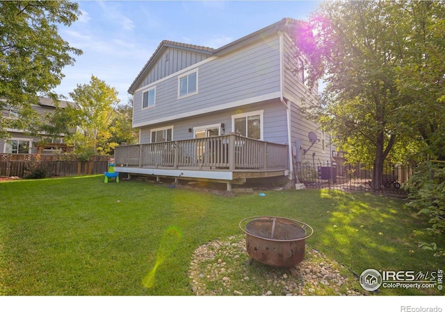 rear view of house featuring a wooden deck, a yard, and an outdoor fire pit