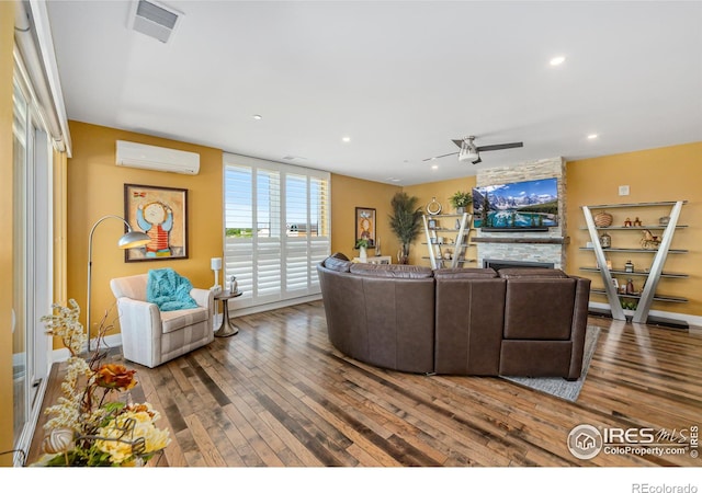 living room featuring ceiling fan, a wall unit AC, and hardwood / wood-style flooring