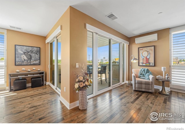 living area featuring dark wood-type flooring and a wall mounted AC